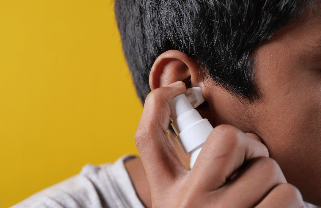 Close-up of hands using earwax removal drops for safe ear cleaning